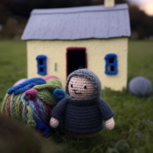 A person made out of yarn standing in front of their home, representing a late-diagnosed autistic person navigating autism independent living.